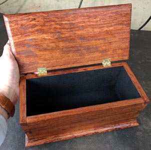 A simple wooden box with a black interior and dovetails at the corners