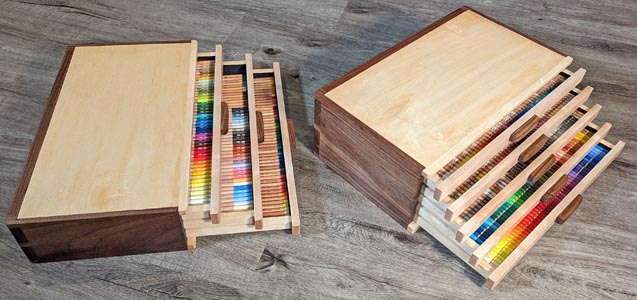 Two pencil storage boxes with drawers partially opened to reveal colorful pencils inside